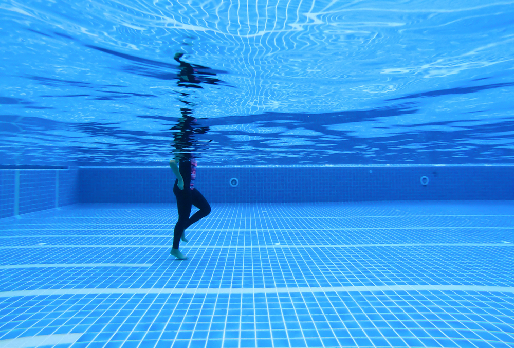 Underwater,Image,Of,A,Woman,Walking,In,A,Swimming,Pool